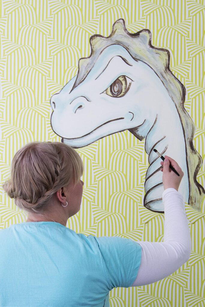 Taitelija maalaamassa seinämaalausta lastenhuoneeseen